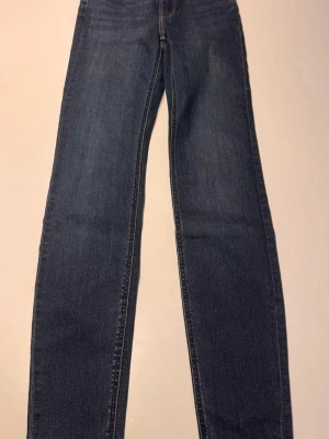 Mörkblå raka jeans storlek 24/31 - Säljer ett par klassiska mörkblå jeans med rak passform. Jeansen har fem fickor och kontrastsömmar. Perfekta till en avslappnad stil och passar till det mesta. Materialet är denim i bomull och de har en tidlös look.