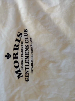 Vit t-shirt från Morris med tryck - Säljer en vit t-shirt från Morris med svart tryck på bröstet där det står 'Morris Gentlemens Club'. Klassisk passform och rund hals. Perfekt till jeans eller shorts för en clean och stilren look.