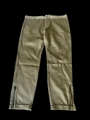 Oanvända Beige chinos GABBA  - Snygga beige chinos med raka ben och dragkedjor vid bensluten ifrån märket GABBA. I nyskick, aldrig använda endast provade 1 gång. Klassisk design med bälteshällor, sidofickor fram och passpoalfickor bak. Tillverkade i ett mjukt och lätt tyg som ger en clean och stilren look.