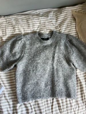 Grå puffärmad stickad tröja Vero Moda - Mysig grå stickad tröja från Vero Modq med puffärmar och rund halsringning. Tröjan har en mjuk och luddig yta. Storlek XL men sitter ungefär som en M eftersom den är lite kortare. Aldrig använd - jag såg att den såg lite nopprig ut därav sista bilden eftersom det är ett fluffigt material och alltså inte nopprig.
