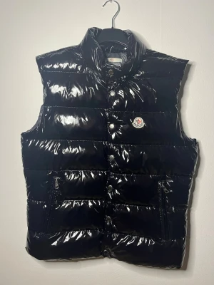 Moncler svart väst - Svart Moncler väst i ny skick, den är storlek 2 som motsvarar storelek S/M, NFC på loggan,  pm vid intresse eller för detaljbilder.