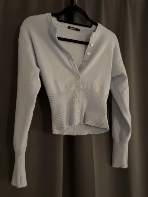 Ljusblå ribbad kofta från Gina Tricot - Snygg ljusblå kofta från Gina Tricot. Tröjan är nästan helt ny men fått en liten fläck vid ärmen som säkert går bort.