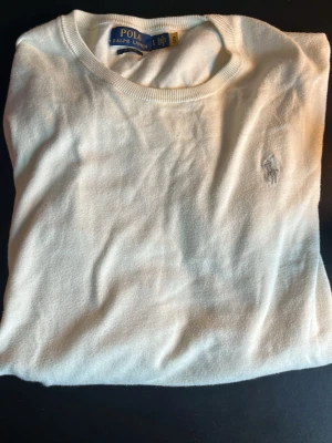 Beige tröja från Polo Ralph Lauren - Klassisk beige tröja från Polo Ralph Lauren med rund halsringning och den ikoniska broderade loggan på bröstet. Tröjan har en enkel och stilren design, perfekt för dig som gillar tidlös stil. Materialet känns mjukt och bekvämt.