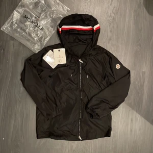 Moncler windbreaker - Jag säljer nu min svarta moncler windbreaker då den inte riktigt passar mig. Jackan är i storlek 2 vilket motsvarar ungefär S-M. Skicket är 10/10 då den knappt har använts och tags samt påsen finns kvar och ingår i köpet🔥vid snabb affär är priset diskuterbart. Nfc scan funkar samt qr koden. Först till kvarn🙌 OBS: Det finns ett hål under än av ärmarna.