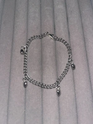 Svart kedjearmband med pärlor - Snyggt armband i svart metall med små svarta pärlor som hänger längs kedjan. Armbandet har en enkel karbinhake och en stilren, modern look. Perfekt för dig som gillar minimalistiska accessoarer med en twist.