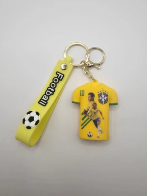 Nyckelring Neymar Jr Brasilien - Gul nyckelring i silikon med motiv av Neymar Jr i Brasiliens landslagströja och texten 'Football' på bandet. Tröjan har gröna detaljer och nummer 10. Perfekt accessoar för fotbollsfans.