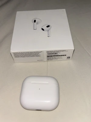 Apple AirPods 3 med laddningsetui - Säljer ett par vita Apple AirPods 3 med trådlöst laddningsetui. Snygg och stilren design i blank plast, perfekt för dig som vill ha smidiga och trådlösa hörlurar med bra ljud och enkel anslutning till iPhone eller andra Apple-enheter. Kommer med originalförpackning.