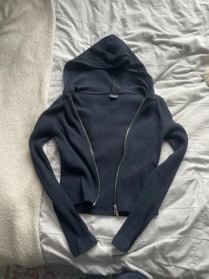 Svart ribbad hoodie från Gina Tricot - Säljer en svart ribbad hoodie från Gina Tricot i storlek S. Hoodien har dragkedja framtill, långa ärmar och en stor huva. Materialet är stretchigt och mjukt, perfekt för en avslappnad och trendig look.