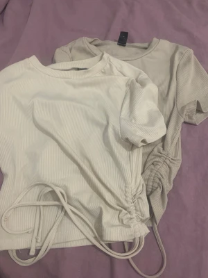 Beige ribbade toppar med snörning SHEIN - Två beige ribbade toppar från SHEIN i storlek S. Båda har korta ärmar, rund halsringning och trendig snörning i sidan som ger en snygg detalj. Materialet är mjukt och stretchigt, perfekt för en avslappnad och stilren look.