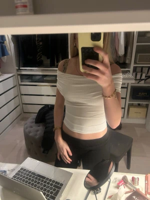 Vit offshoulder croppad topp - Säljer en vit, croppad offshoulder topp med tight passform. Toppen har en enkel och stilren design utan mönster och är perfekt för dig som gillar trendiga och minimalistiska plagg. Materialet känns mjukt och stretchigt, troligen bomull eller polyester.