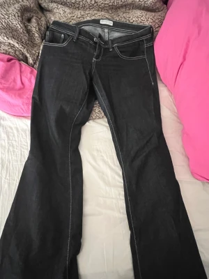Svarta bootcut jeans med vita sömmar - Snygga mörk blåa bootcut jeans med kontrasterande vita sömmar och klassisk femficksdesign. Från fina tricot i bra skick säljer pågrund av att de inte passar mej längre, pris kan diskuteras❣️