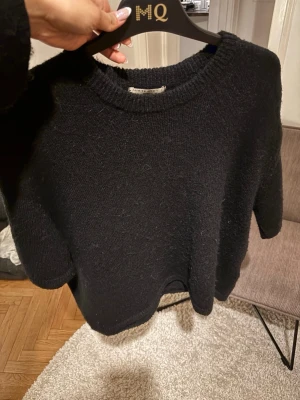 Svart stickad tröja från Ginatricot  - En enkel och stilren svart stickad tröja med armbågslånga armar från Ginatricot. Tröjan har rund halsringning, raka ärmar och är gjord i ett mjukt, lite luddigt material som känns skönt mot huden. Perfekt för lager på lager och passar till det mesta🩷