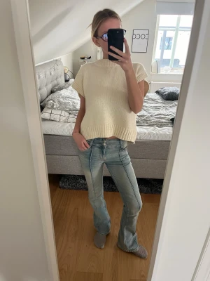 Ljusblå bootcut jeans med kontrastsömmar - Säljer ett par ljusblå bootcut jeans med snygga kontrastsömmar och klassisk femficksdesign. Jeansen har låg midja och är tillverkade i denim med stretch för en bekväm passform. Perfekta för dig som gillar en avslappnad och trendig look.