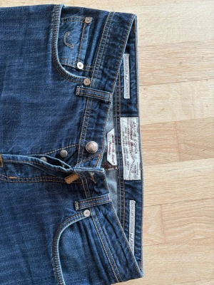 Mörkblå jeans från Jacob Cohen - Snygga mörkblå jeans från Jacob Cohen med klassisk femficksmodell och raka ben. Jeansen har kontrastsömmar och silverfärgade knappar. Tillverkade i mjukt denimtyg som ger en skön passform. Perfekta för en avslappnad och trendig look.