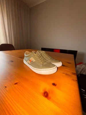 Olivgröna sneakers från Polo Ralph Lauren - Snygga olivgröna sneakers från Polo Ralph Lauren med klassisk låg profil och vit sula. Skorna har en orange logga på sidan och är gjorda i en mix av textil och syntetmaterial. Perfekta för en avslappnad och trendig stil. Har använt dom här skorna 2 gånger!