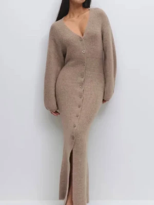 Beige stickad långklänning (Gina Tricot) - Mysig trendig beige stickad långklänning med v-ringning och stora knappar framtill. Klänningen har långa ärmar och en slits nedtill, vilket ger en avslappnad men ändå stilren look. Perfekt för dig som gillar en enkel men trendig stil. Går perfekt att styla till ett par byxor också. Den är använd 1 gång. Den är helt slutsåld på hemsidan.❣️