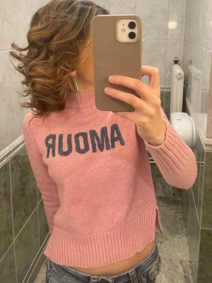 Zadig & voltaire tröja  - Säljer en rosa stickad tröja från zadig & voltaire med mörkblå text 'AMOUR' på bröstet. Tröjan har ribbstickade muddar vid ärmslut och nederkant samt en högre rund halsringning. Perfekt för dig som gillar en avslappnad men trendig stil. Har ett litet hål vid ärmen 