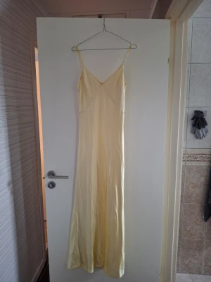 Gul balklänning  - Elegant långklänning i ljusgul nyans med smala axelband och v-ringad urringning. Passar perfekt till bal eller lärarmiddag. Nypris ligger på 1050 kr. Endast använd 1 gång!💕.