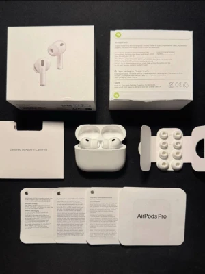 Apple AirPods Pro 3 - AirPods Pro från Apple med vit laddningsetui och flera utbytbara silikonproppar. Hörlurarna är trådlösa och har en stilren, kompakt design i vitt. Medföljer originalförpackning, manualer och extra öronproppar för perfekt passform.