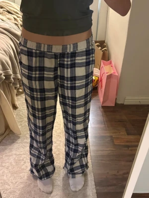 Rutiga pyjamasbyxor i blått och vitt - Mysiga pyjamasbyxor med blåvitt rutmönster och resår i midjan. Byxorna har en avslappnad passform och är perfekta för chill hemma. Tillverkade i mjukt tyg som känns skönt mot huden.