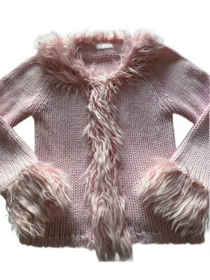 Rosa stickad kofta med fluffiga detaljer y2k style  - Så fin stickad kofta med fluffiga detaljer y2k style. Koftan är från H&M tidigt 2000-tal. Storleken är tyvärr bortklippt men jag skulle gissa på att den är en 140.  Skriv för mått om du önskar. OBS liten fläck och lite tyg som åkt upp men märks inte så tydligt. Se sista bild.