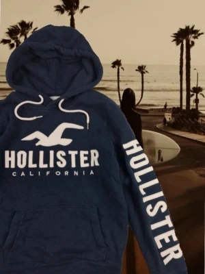 Hollister hoodie blå, unik model - Blå Hollister hoodie i unik model i bra sick Inga defekter. Storlek S/M är S men lite stor S skulle säga mittemellan S och M