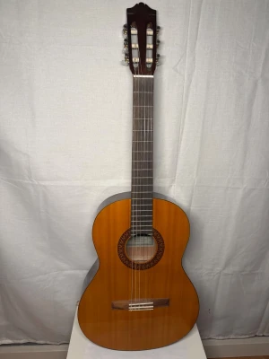 Yamaha klassisk gitarr CS45 - Säljer en klassisk akustisk gitarr från Yamaha, modell CS45. Gitarren har en naturlig träfärg med dekorativ rosett runt ljudhålet och sex nylonsträngar. Kroppen är i trä och halsen är mörkare trä. Perfekt för dig som vill börja spela eller behöver en extra gitarr.