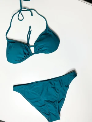 Turkos bikini med knyt - Snygg turkos bikini med trekantsöverdel och knyt i nacken samt baktill. Klassiska bikinitrosor med enkel design. Perfekt för lata dagar på stranden eller poolen.