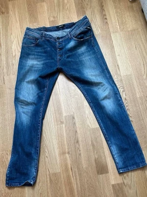 Blå replay jeans. Har knappt använt dem.  - Säljer ett par klassiska blå jeans med raka ben och knappgylf. Jeansen har fem fickor, snygga slitningar och kontrastsömmar. Perfekta för en avslappnad och trendig look. Materialet är denim i bomull.
