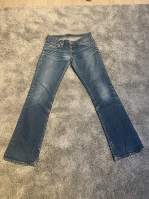 Blå bootcut jeans från Nudie Jeans - Bootcut nudie jeans, storleks och model lappen är utsuddad , så är osäker på vilken modell detta är fast de är lågmidjade och bootcut. Lappen där bak har också blivit borttagen! det verkar vara storlek W29 L30 baserat på mått. Midja 38-38,5cm, ytterbenslängd 97cm, benöppning 20,5cm ⚠️Mått kan ha felmarginal på 1-2cm men det är osannolikt! 