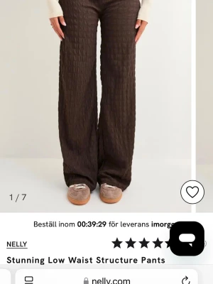 Low waist structure pants Nelly - Säljer ett par bruna low waist byxor från Nelly med strukturerat tyg och raka, vida ben. Byxorna har en modern passform och är perfekta för dig som gillar trendiga och bekväma plagg. Materialet har en snygg textur som ger extra stilpoäng.