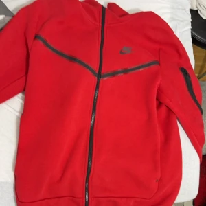 Röd Nike tech - En röd fin Nike tech köpt i JD som är knappast använd och är i 9/10 skick inga hål eller nåt säljer pga för liten kan mötas upp är i malmö eller frakta.
