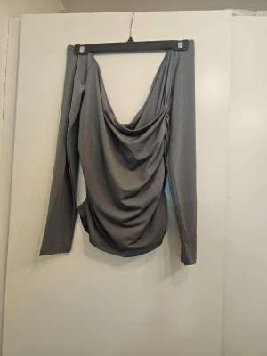 Svart långärmad omlottopp small packet - Snygg grå långärmad topp med omlott och draperad front. Toppen har en loose passform och djup urringning framtill. Perfekt att styla med jeans eller kjol för en trendig look.small packet