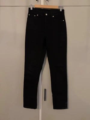 Svarta skinny jeans - Snygga svarta skinny jeans med hög midja och klassisk femficksdesign från Weekday. Jeansen har smal passform. Storlek W26 L30. 