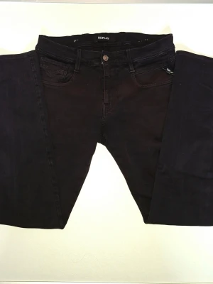 Svarta jeans från Replay - Snygga svarta jeans från Replay med klassisk femficksdesign och raka ben. Jeansen har en diskret logga vid fickan och är tillverkade i ett stretchigt bomullsmaterial för skön passform.