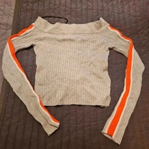 Tröja H&M S - Ribbad offshoulder tröja med ränder  Snygg ribbad stickad tröja i beige med offshoulder-design. Långa ärmar med orange och vit rand längs hela armen ger en sportig vibe. Tröjan är tight och croppad, perfekt att matcha med höga jeans eller kjol.  Kan även hämtas I Partille  E1