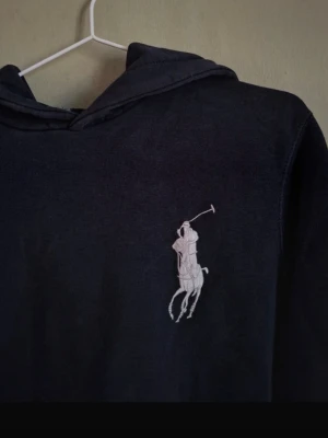 Mörkblå hoodie från Polo Ralph Lauren🙌🤩 - Mörkblå hoodie från Polo Ralph Lauren med stor vit broderad polospelare på bröstet och siffran 3 med texten POLO på ärmen. Klassisk huva och känguruficka framtill. Perfekt för en avslappnad och sportig stil.🙌🤩
