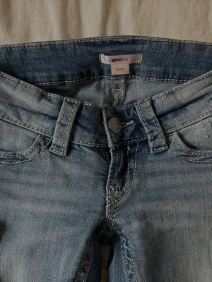Ljusblå slitna jeans från Gina Tricot - Ljusblå jeans från Gina Tricot i storlek XS med slitningar på benen och klassisk femficksdesign. Jeansen har en lätt utsvängd passform och är tillverkade i denim med snygg tvättad look. Perfekt för dig som gillar en trendig och avslappnad stil.
