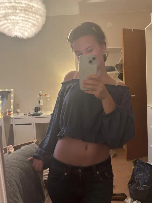Blå offshoulder croppad topp H&M - Säljer en blå croppad offshoulder-top från H&M:s DIVIDED-kollektion. Toppen har långa puffärmar och resår vid axlar och midja för en snygg passform. Perfekt för dig som gillar trendiga och bekväma plagg med lite edge.