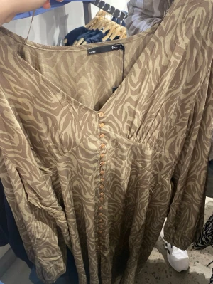 Beige långklänning med zebramönster - Snygg beige långklänning från Lager 157 med zebramönster och v-ringning. Klänningen har aldrig används, köpt i för stor storlek därav säljs den. 