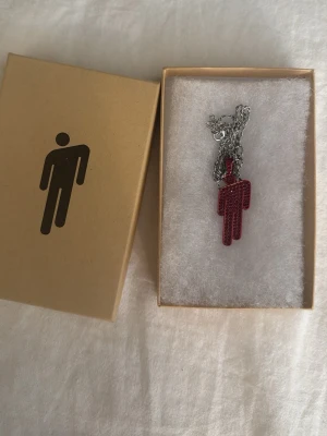 Billie Eilish Blohsh - Äkta Billie Eilish blohsh halsband med ett hänge i form, täckt av röda gnistrande stenar. Hänget hänger på en silverfärgad kedja. Kommer i original ask och är köpt från hennes hemsida. Köpte den för ish 950kr