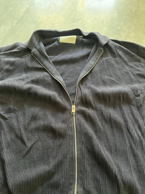 Mörkgrå ziptröja från Jack & Jones - Säljer en mörkgrå ribbstickad ziptröja från Jack & Jones. Tröjan har hel dragkedja framtill och klassisk krage. Perfekt för lager-på-lager och enkel att matcha med andra plagg. Pris går att diskutera!