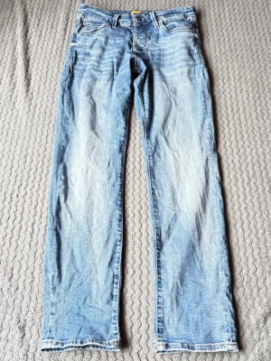 Ljusblå Slim jeans från Jack & Jones - Ljusblå jeans från Jack & Jones med raka ben och klassisk femficksdesign. Jeansen har en snygg tvättad look med slitningar och är tillverkade i bomullsdenim. Perfekta för en avslappnad och trendig stil. Passform slim