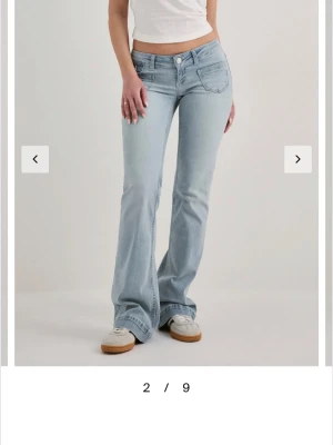 Ljusblå bootcut jeans - Säljer ett par ljusblå bootcut jeans med låg midja och klassiska fem fickor. Jeansen har en lätt tvättad look och vida ben nedtill. Perfekta för en avslappnad och trendig stil.