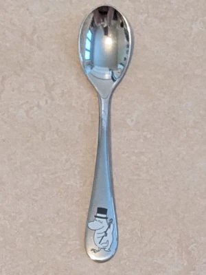 Barnsked med MUMINMOTIV - Söt liten sked i rostfritt stål med ett ingraverat Muminmotiv längst ner på handtaget. Perfekt storlek för barn och har en klassisk silverfärg med en blank finish. Motivet föreställer Mumin med hatt.