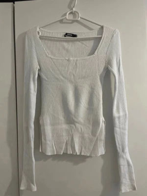 Vit ribbad långärmad topp Bik Bok - Säljer en vit ribbad topp från Bik Bok med lång ärm och fyrkantig ringning. Toppen är figurnära och har en stretchig passform som sitter snyggt på kroppen. Perfekt att styla med jeans eller kjol för en clean look.