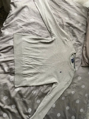 Ljusgrå tröja från Polo Ralph Lauren - Snygg ljusgrå tröja från Polo Ralph Lauren med rund halsringning och diskret broderad logga på bröstet. Tröjan har långa ärmar och ribbade muddar vid ärmslut och nederkant. Perfekt för en clean och stilren look.