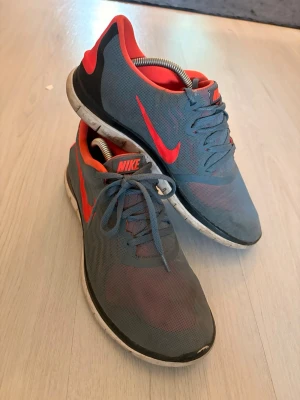 Nike free run 4.0 - Snygga sneakers från Nike i grå mesh med röda detaljer och logga. Skorna har lågt skaft, vita sulor och röda insidor. Perfekta för dig som gillar sportig stil och vill ha bekväma skor till vardags. Klassisk snörning och lätt material. Inte bara snygga utan grymma att jogga i )