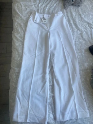 Vita vida byxor från Bik Bok - Vita kostymbyxor från Bik Bok med hög midja och vida ben. Materialet är lätt och ger en clean look, perfekt för dig som gillar stilrena outfits 🤍