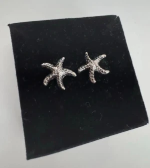 Snygga örhängen i form av sjöstjärnor - oanvända - Ett par silvriga örhängen formade som sjöstjärnor. De har en detaljerad yta som ger en cool och unik look. Perfekta för dig som gillar havsinspirerade accessoarer. 
